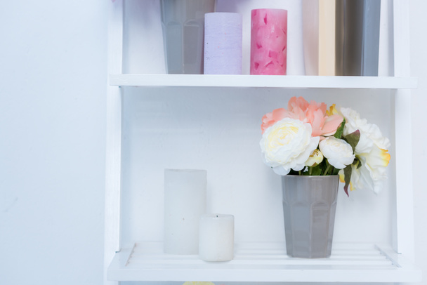 close-up view of white wooden shelves with books, candles and flowers in vase - Photo, Image