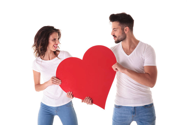 casual young man and woman fighting over a big heart - Photo, Image