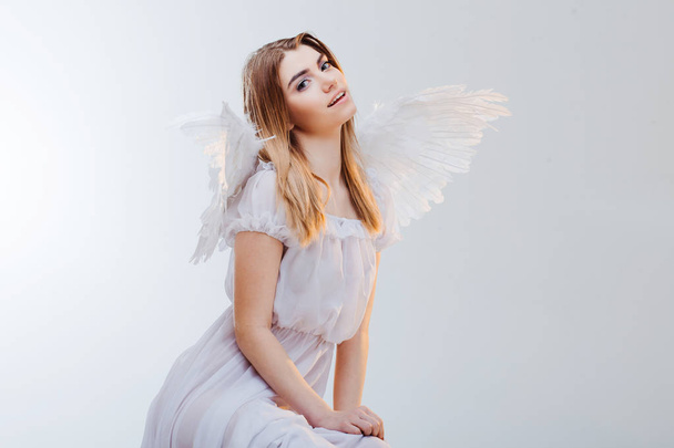An angel from heaven. Young, wonderful blonde girl in the image of an angel with white wings. Portrait close-up - Foto, Bild