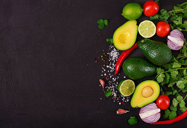 Ingredientes de salsa de guacamole: aguacate, tomate, cebolla, chile, ajo, cilantro, lima sobre fondo negro. Vista superior
 - Foto, Imagen