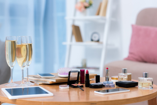 lähikuva gadgetit, lasit samppanjaa ja erilaisia kosmetiikka pöydällä
  - Valokuva, kuva