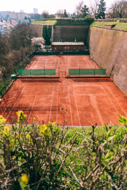 Gran cancha de tenis de barro sin personas en el día del sol, vista superior
  - Foto, Imagen