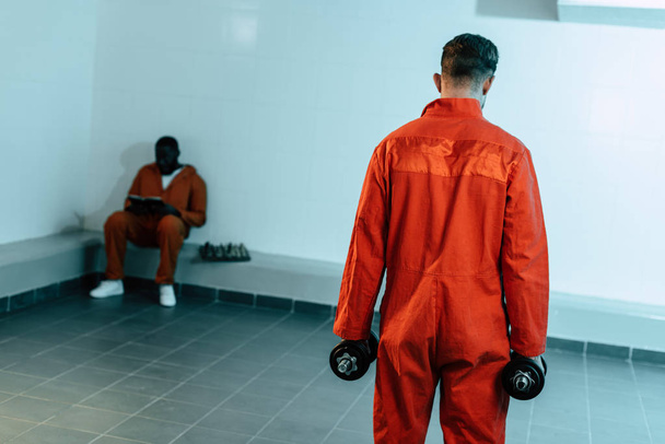 vue arrière de l'entraînement des prisonniers avec haltères dans la cellule de prison
 - Photo, image