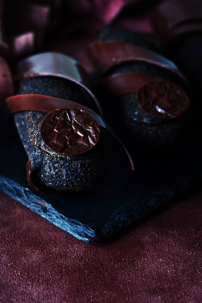 Black chocolate eclair with truffle coating on a dark background. An exquisite French dessert. - Photo, Image