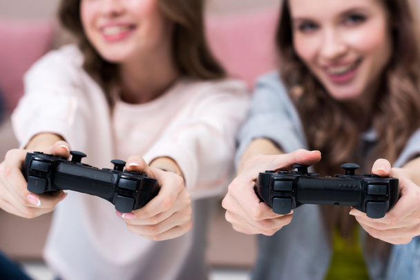 cropped shot of happy girls playing with joysticks together - 写真・画像