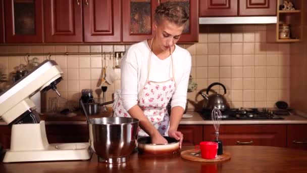 Chica está engrasando bandeja para hornear con aceite en la cocina casera moderna
 - Imágenes, Vídeo