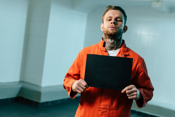 prisoner holding blackboard and looking at camera - Foto, Imagem