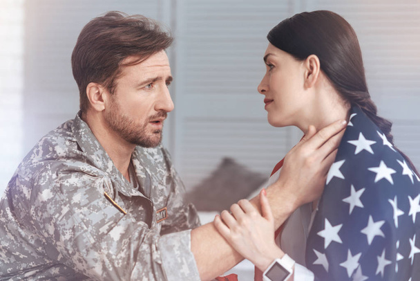 Military husband comforting anxious wife covered in USA flag - Foto, afbeelding