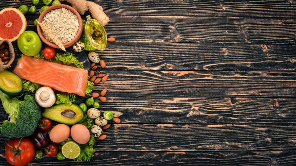 Healthy food. Fish salmon, avocado, broccoli, fresh vegetables, nuts and fruits. On a wooden background. Top view. Copy space. - Photo, Image