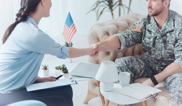 Thankful military servant shaking hands with female therapist - Foto, imagen