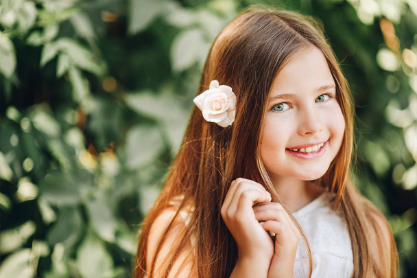 Outdoor portrait of adorable little girl with white rose flower - Фото, зображення