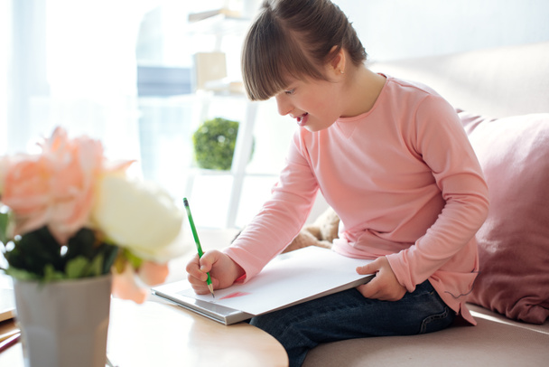 Aranyos gyermek down-szindrómás ceruzával - Fotó, kép