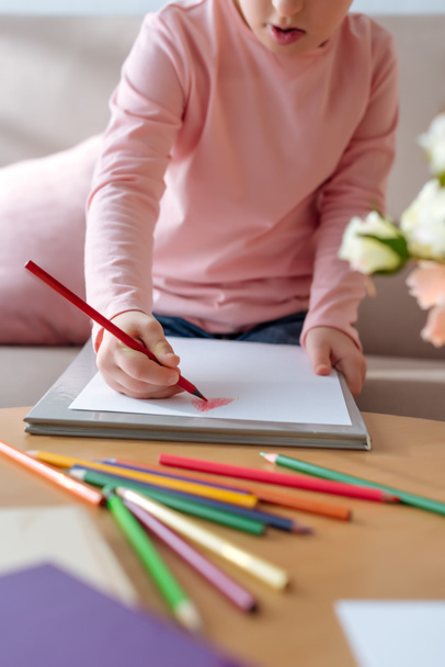 Γκρο πλαν θέα του παιδιού με σύνδρομο down σχέδιο με χρωματιστά μολύβια - Φωτογραφία, εικόνα