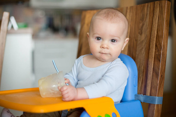 Piccolo bambino, mangiare purè di cibo per la prima volta
 - Foto, immagini