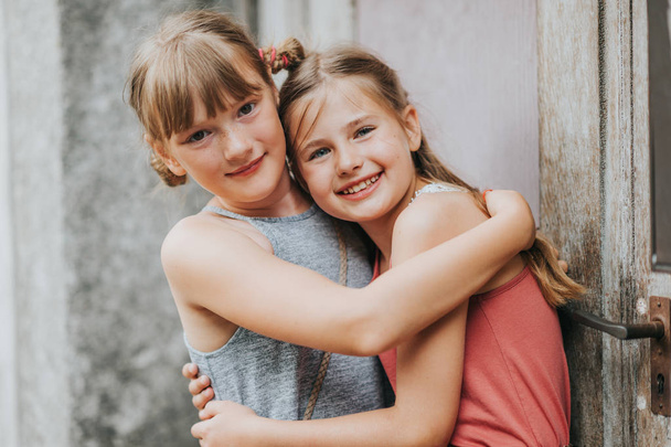Summer portrait of two adorable kid girls hugging each other - Photo, Image