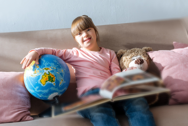 Enfant atteint du syndrome du duvet lire le livre et jouer avec le globe
 - Photo, image