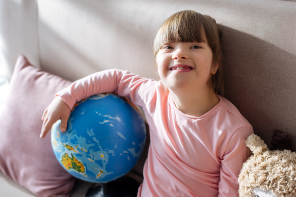 Smiling child with down syndrome holding globe - Fotoğraf, Görsel