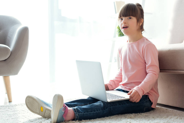 A gyermek down-szindrómás használ laptop, miközben ül a földön - Fotó, kép