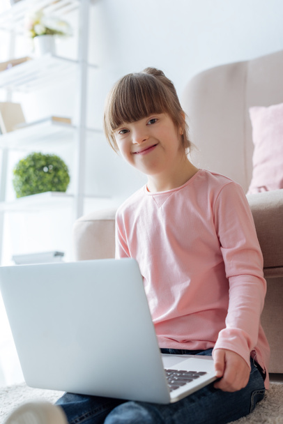 Smiling kid with down syndrome using laptop - Фото, изображение