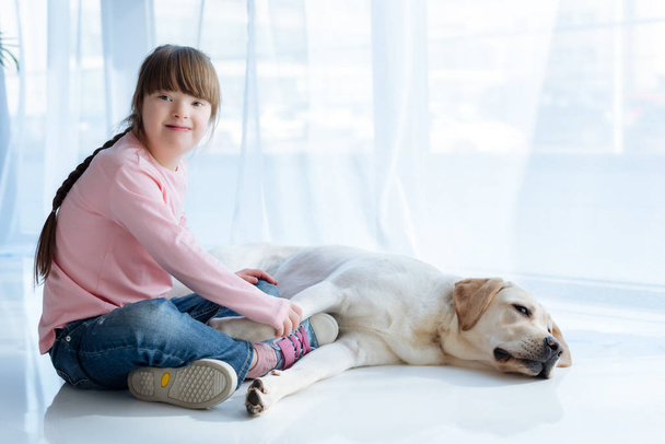 Kid with down syndrome holding Labrador dog paw  - Zdjęcie, obraz