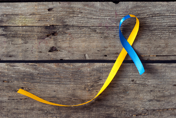 Ημέρα για το σύνδρομο Down κορδέλα μπλε και κίτρινο στο φόντο ξύλινη - Φωτογραφία, εικόνα