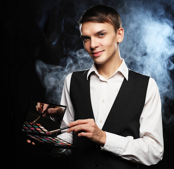 Professional makeup artist posing in studio, holds a palette of  - Фото, изображение