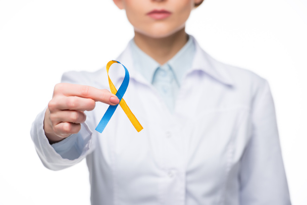 Female doctor holding blue and yellow ribbon for Down Syndrome Day isolated on white - Фото, изображение