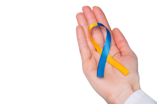 Female hand with Down Syndrome Day ribbon isolated on white - Photo, Image