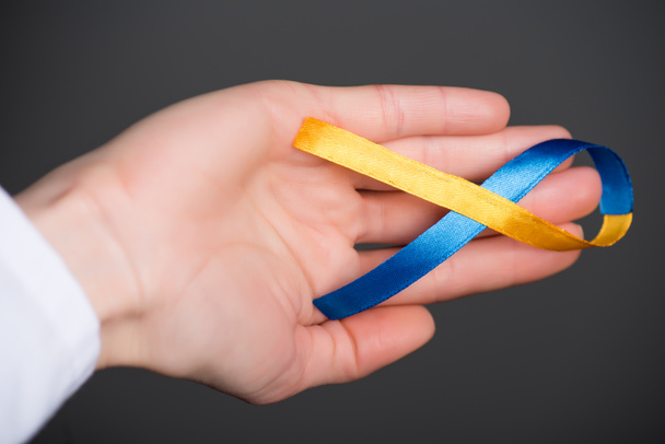 Female hand with Down Syndrome Day ribbon isolated on grey - Fotoğraf, Görsel