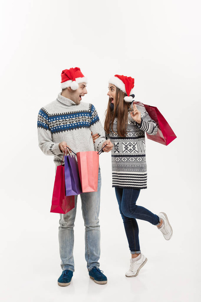Χριστούγεννα Concept - πλήρες μήκος ελκυστικό ζευγάρι κρατώντας τσάντες αγορών που απομονώνονται σε λευκό φόντο γκρι. - Φωτογραφία, εικόνα