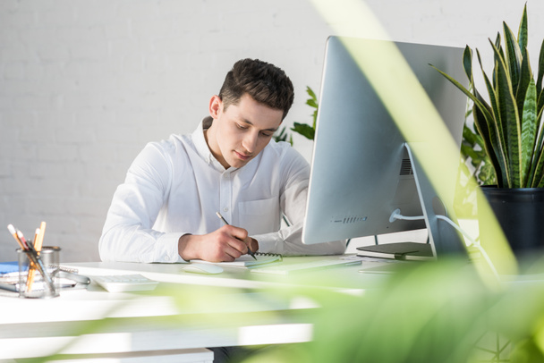 focused young businessman writing notes at workplace - Foto, Bild