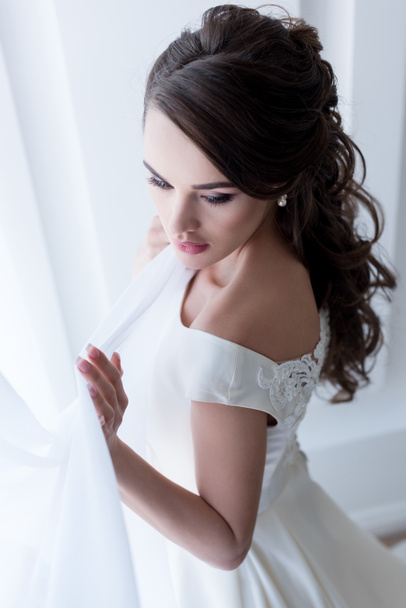 приваблива брюнетка жінка позує у весільній сукні
 - Фото, зображення