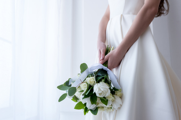 abgeschnittene Ansicht der Braut in traditionellem Kleid mit Brautstrauß - Foto, Bild