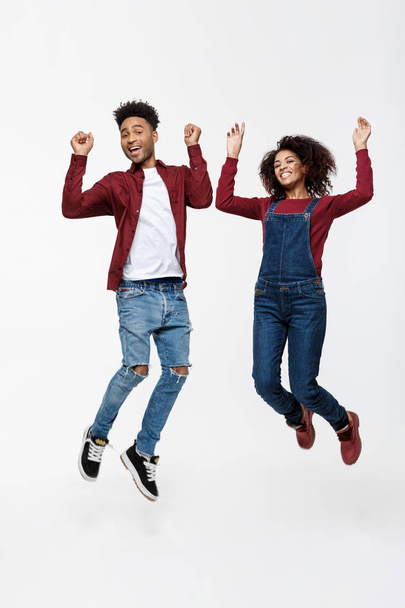 Elämäntapa, onnellisuus ja ihmiset käsite: Onnellinen nuori ihana afroamerikkalainen pari hyppää kirkkaan harmaan taustan yli
. - Valokuva, kuva
