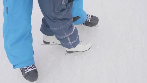 The first steps of a young child on skates. Dad teaches the child to skate and holds his hands . Family and outdoor activities - Footage, Video