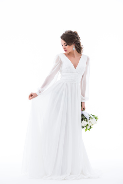 brünette Braut posiert in elegantem weißen Kleid mit Brautstrauß, isoliert auf weiß - Foto, Bild