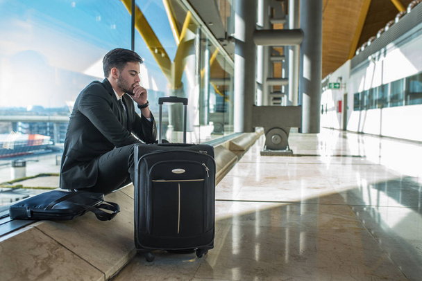 a reptéren várja az ő késésben levő járatra csomagokkal ideges fiatal üzletember - Fotó, kép
