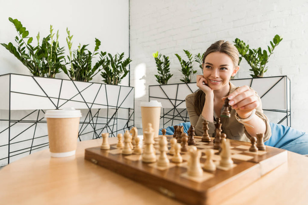 Nahaufnahme einer lächelnden jungen Frau beim Schachspielen - Foto, Bild