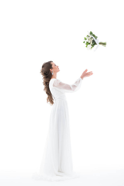 brunette bride in white dress throwing wedding bouquet, isolated on white - Fotoğraf, Görsel