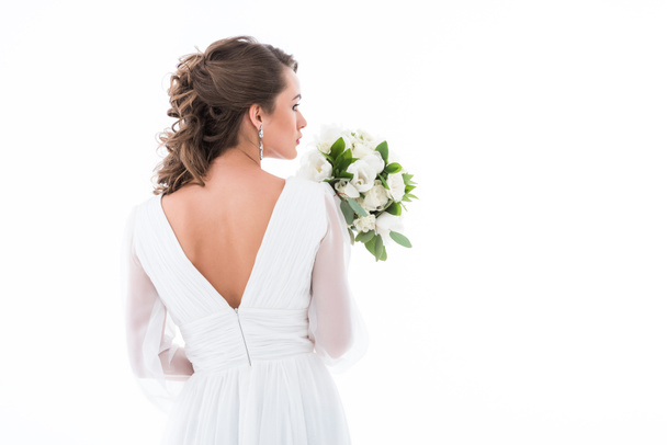 back view of bride in white dress holding wedding bouquet, isolated on white - Фото, изображение