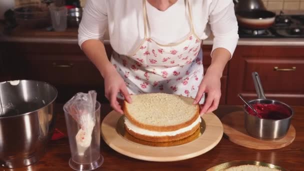 Mulher cozinheiro está colocando em um boleto de bolo um biscoito redondo, de pé em uma cozinha
 - Filmagem, Vídeo