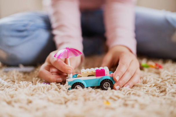 niña jugando con coche de juguete de plástico en la alfombra en casa
 - Foto, imagen