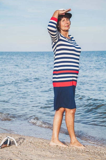 Pretty pleased elderly woman in sea suit on beach - Foto, immagini