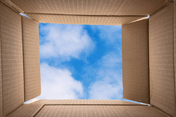 Мислення поза коробкою. Концептуальне зображення креативного мислення: фотографія внутрішньої частини відкритої картонної коробки з тлом блакитного неба. Копіювати пробіл
 - Фото, зображення
