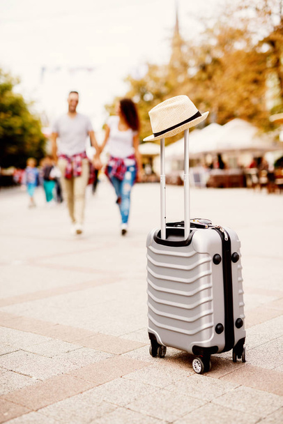 joven pareja de amor feliz viajando por la ciudad, maleta en primer plano
 - Foto, imagen