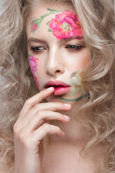 Beautiful blond girl with curls and a floral pattern on the face. Beauty flowers. - Photo, image