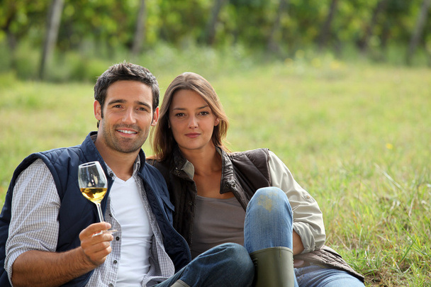 Couple having a glass of wine by a vineyard - Фото, зображення