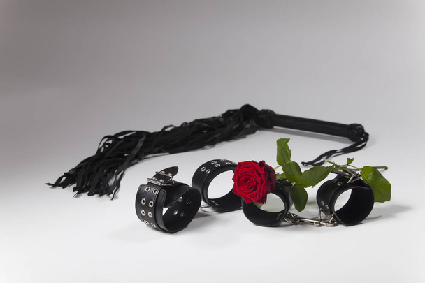 close-up photo of red rose flower with leather handcuffs  - Fotografie, Obrázek