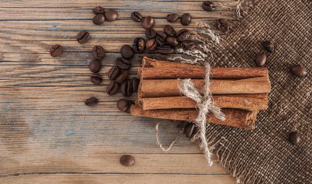 Montón de granos de café, palitos de canela en madera vieja
.  - Foto, Imagen