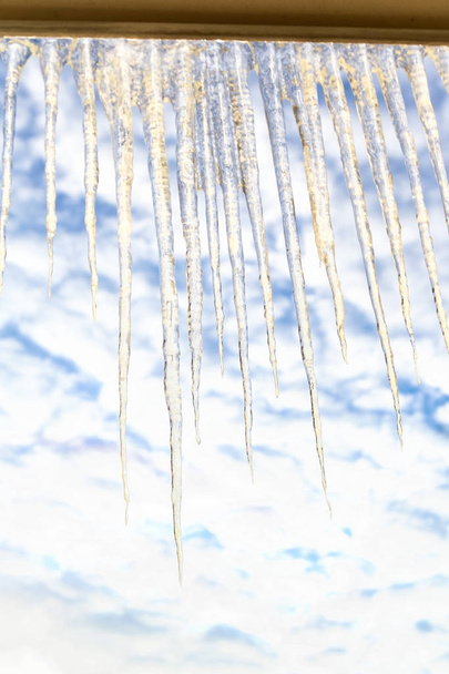 Suurten kuohuviinien jääpuikkojen rivi taivaan ikkunankehyksessä
 - Valokuva, kuva